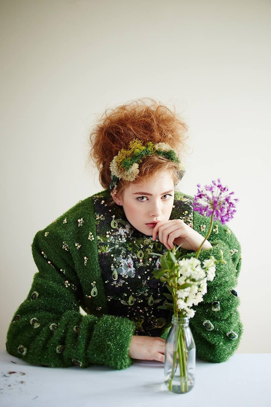 Red-haired model in a lush green textured garment with flowers.