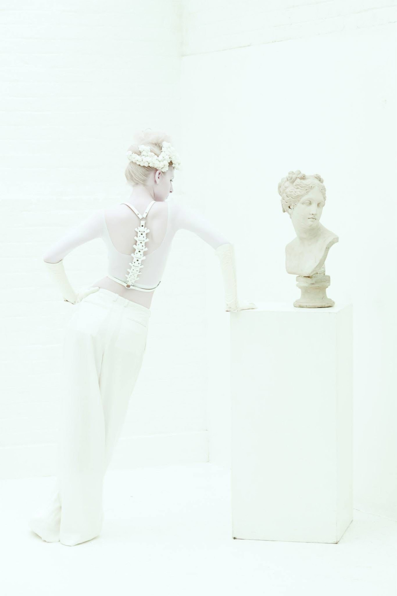 Airy ivory studio; model viewed from the back beside a classical bust.