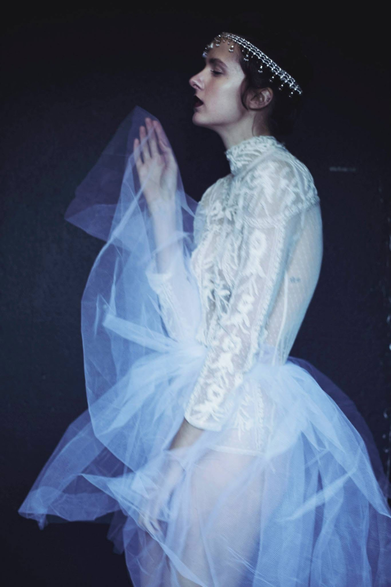 Dramatic dark blue-and-white tulle portrait against a black background.